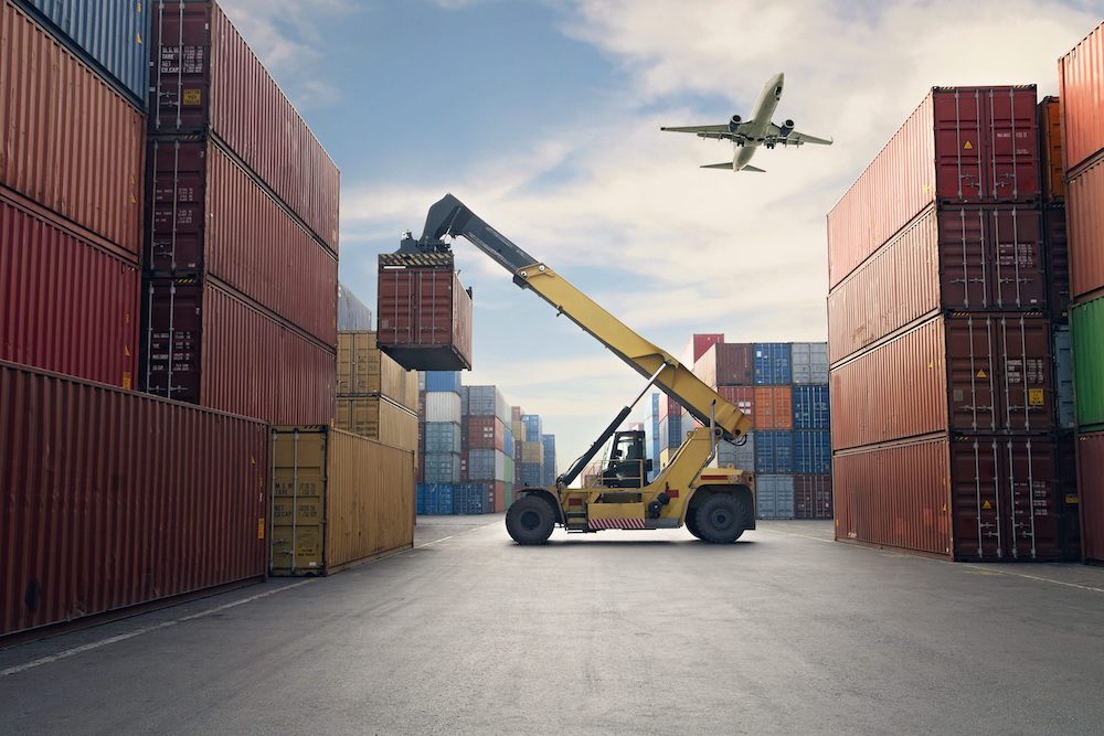 Avión de carga despegando, junto a un muelle de transporte logístico aéreo.