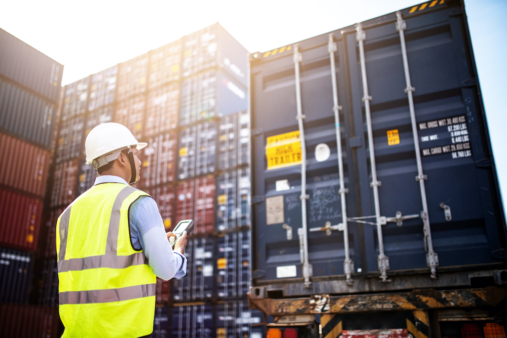 Trabajador revisando contenedores destinados al transporte logístico